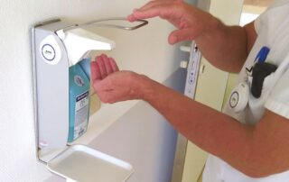 Medizinischer Mitarbeiter desinfiziert sich die Hände an einem Desinfektionsmittelspender mit GWA-Transponder